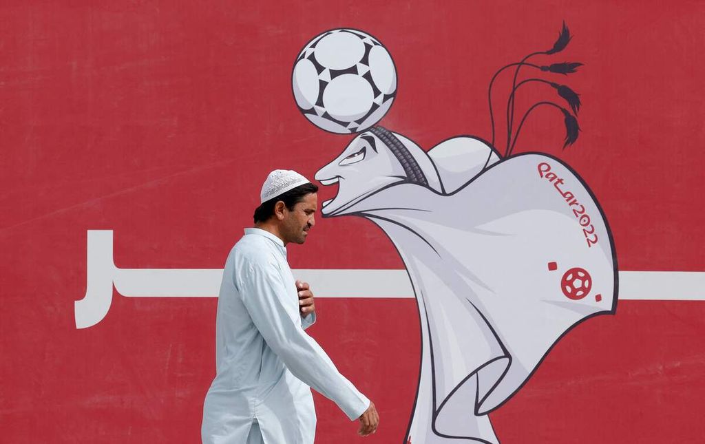 Seorang pria melintas di depan poster La'eeb, maskot Piala Dunia Qatar 2022, di Doha, Qatar, Rabu (9/11/2022). Suasana Kota Doha lebih semarak seiring akan berlangsungnya Piala Dunia. 