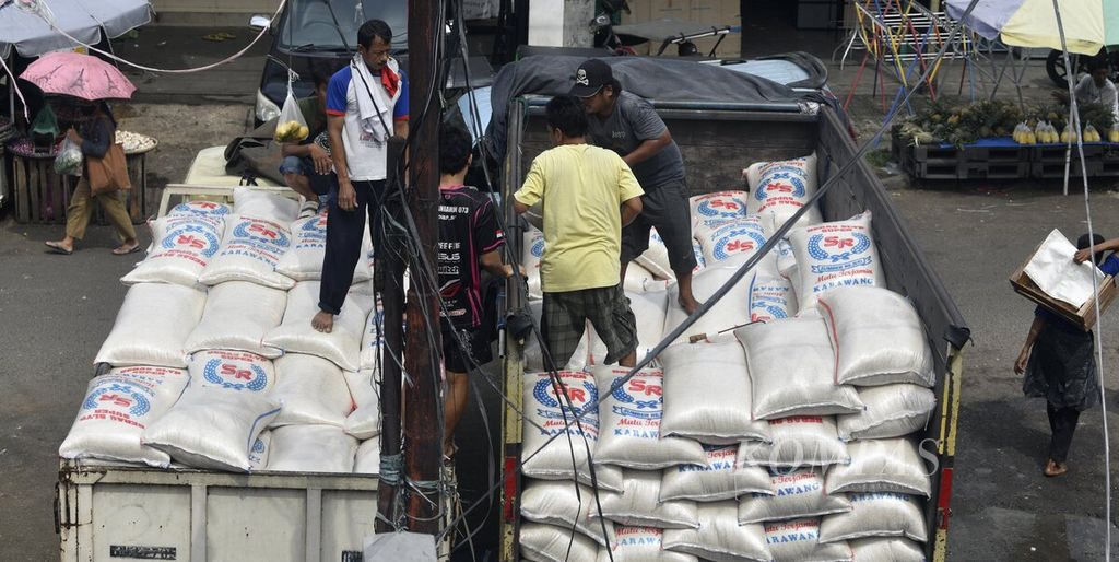 Sejumlah pekerja memindahkan beras dari truk pengangkut di Pasar Anyar, Kota Tangerang, Banten, Selasa (29/3/2022).