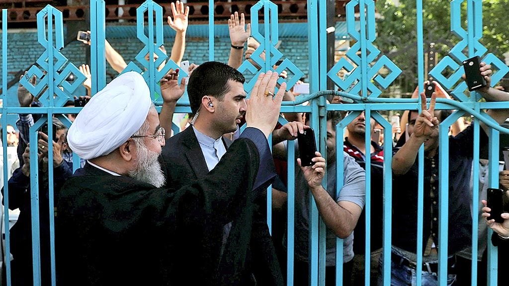 Calon presiden petahana Hassan Rouhani (kiri), Jumat (19/5), di sebuah tempat pemungutan suara di Teheran, Iran, melambaikan tangan kepada para pendukungnya dalam pemilihan presiden Iran 2017. 