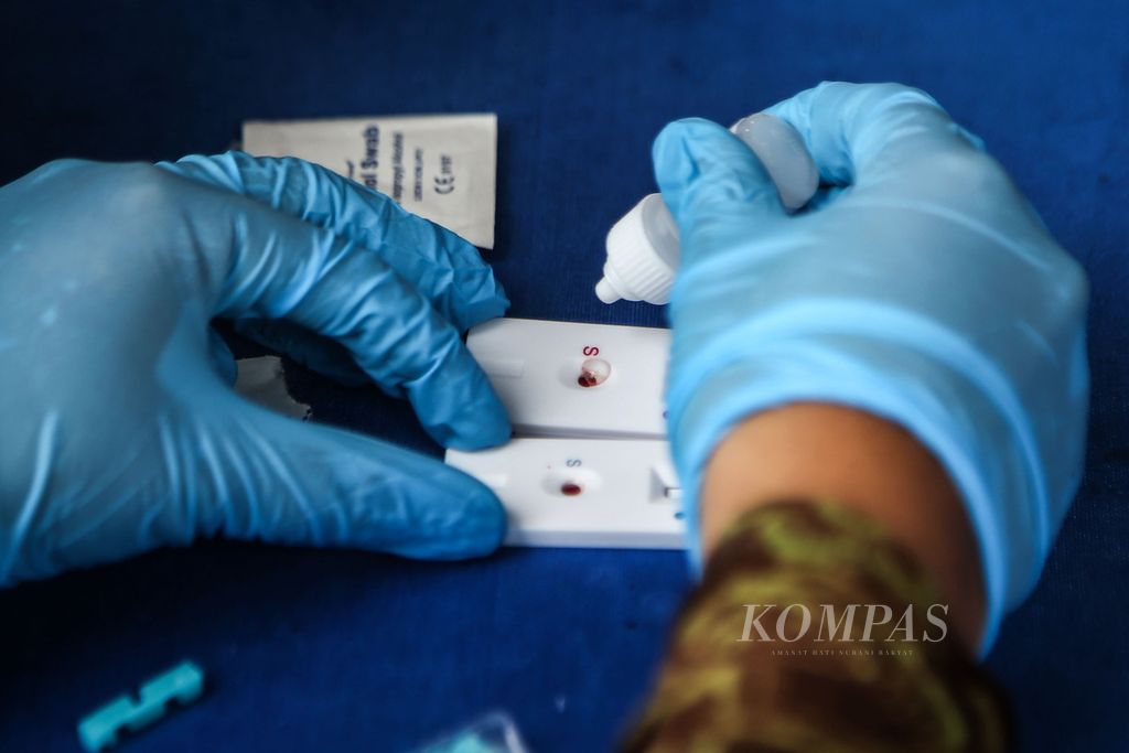 Petugas mengambil sampel darah untuk tes cepat antibodi secara gratis di pos pengamanan Natal dan Tahun Baru, Pamulang, Tangerang Selatan, Banten, Jumat (25/12/2020). 