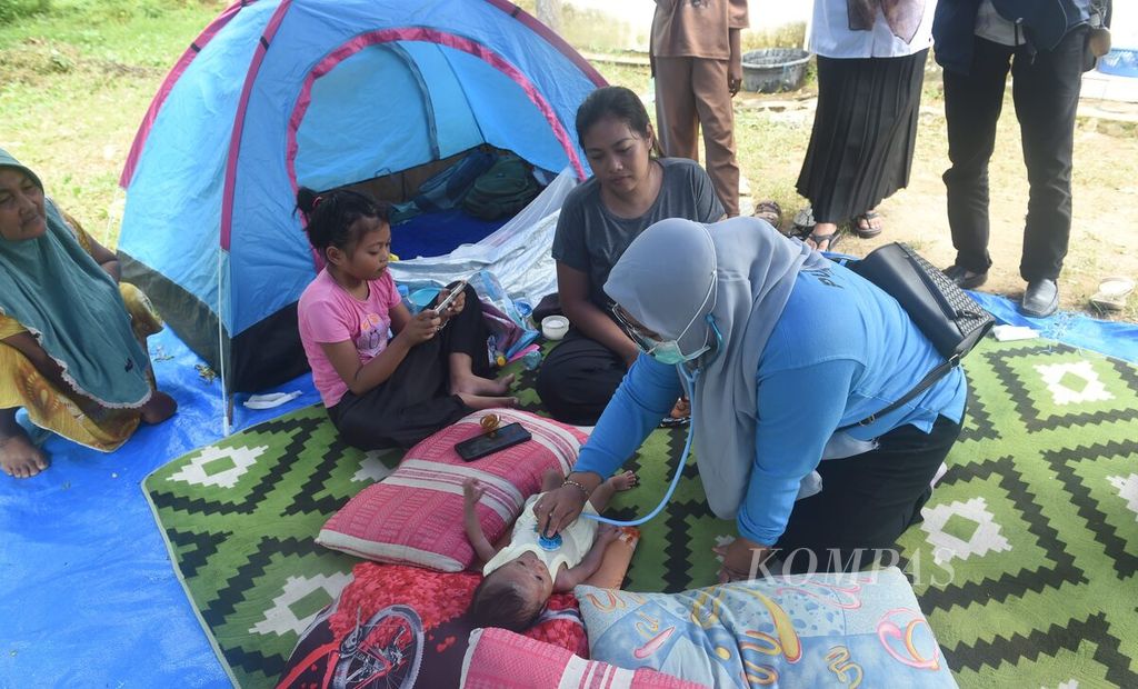 Tenaga kesehatan Puskesmas Sangkapura memeriksa kesehatan bayi di pengungsian korban gempa Desa Dekatagung, Kecamatan Sangkapura di Pulau Bawean, Gresik, Selasa (26/3/2024). 