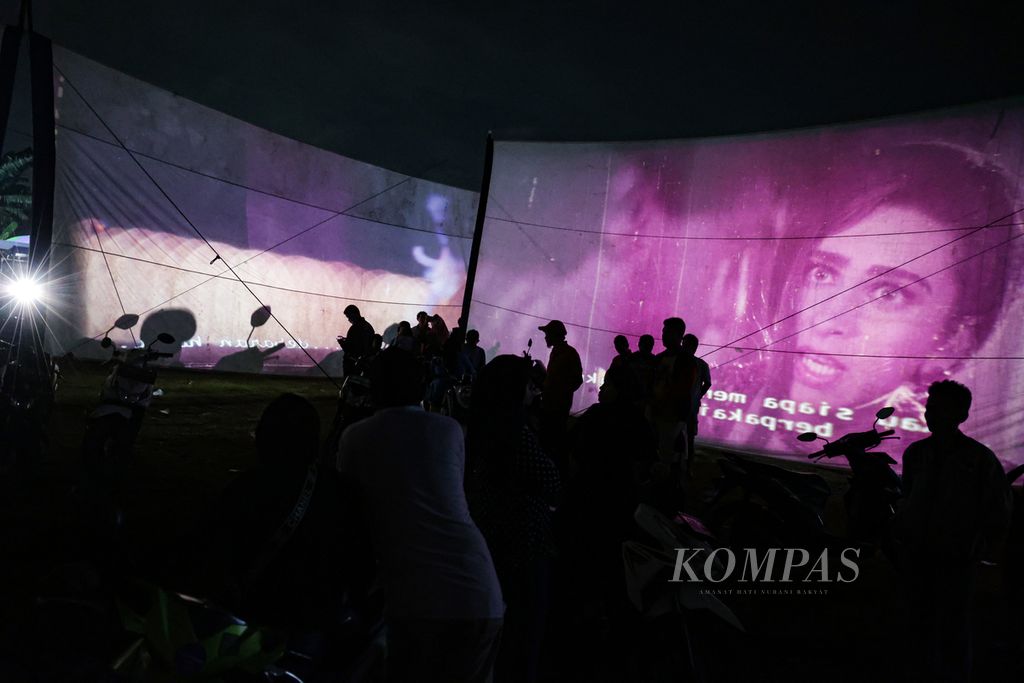 Antusiasme warga saat menyaksikan film layar tancap dalam festival layar tancap di Babakan, Kecamatan Setu, Tangerang Selatan, Banten, Rabu (18/1/2023) malam. Sebanyak 21 layar dibentangkan untuk memutar berbagai genre film dalam festival tersebut. 