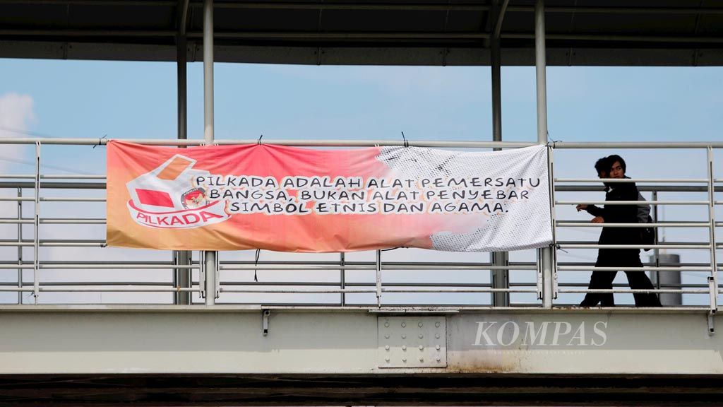 Sebuah spanduk imbauan bagi warga DKI Jakarta untuk menyukseskan pemilihan kepala daerah terpasang di kawasan Cililitan, Jakarta Timur, Rabu (29/3). 