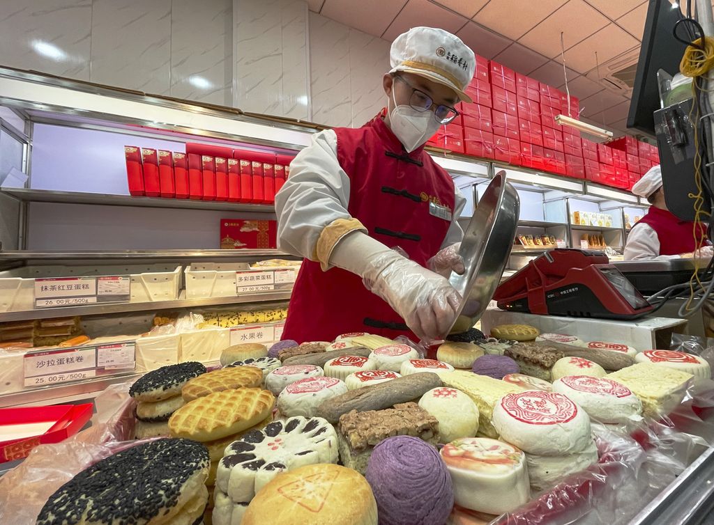 Seorang pekerja mengisi kotak-kotak hadiah tahun baru imlek dengan kue-kue tradisional di cabang toko roti Daoxiangcun, salah satu toko roti di China yang paling terkenal di Beijing, China, 14 Januari 2023 lalu. 