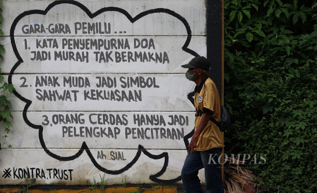 Warga melintas di dekat mural bertema Pemilu 2024 di kawasan Setu, Tangerang Selatan, Banten, Minggu (28/1/2024). 