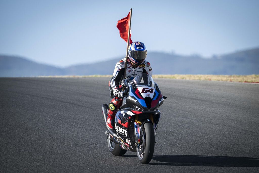 Toprak Razgatlioglu membawa bendera Turki saat merayakan kemenangan dalam balapan dua Superbike seri Portugal di Portimao, Minggu (11/8/2024). Pebalap tim Rokit BMW Motorrad WorldSBK itu kini memegang rekor 13 kemenangan beruntun. Dia juga semakin kokoh di puncak klasemen dengan 365 poin.