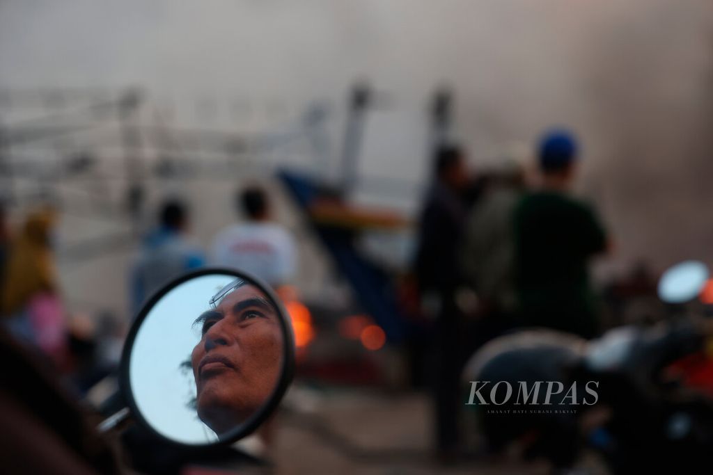 Kaca spion kendaraan merefleksikan warga menyaksikan bencana kebakaran kapal nelayan di Pelabuhan Perikanan Pantai Tegalsari, Kota Tegal, Jawa Tengah, Selasa (15/8/2023). 
