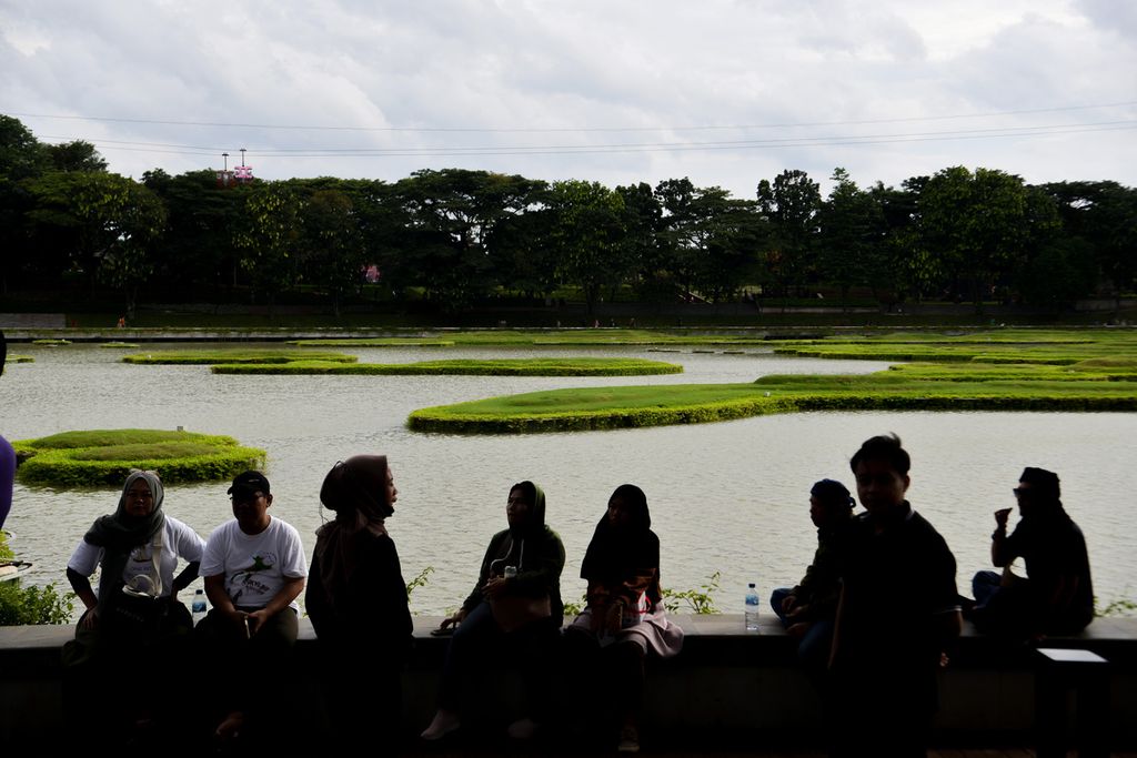 Siluet sejumlah warga bersantai di kawasan Danau Archipelago di Taman Mini Indonesia Indah, Jakarta Timur, Minggu (1/1/2023). Taman Mini Indonesia Indah menjadi salah satu tempat pilihan masyarakat untuk menghabiskan libur panjang Tahun Baru 2023.