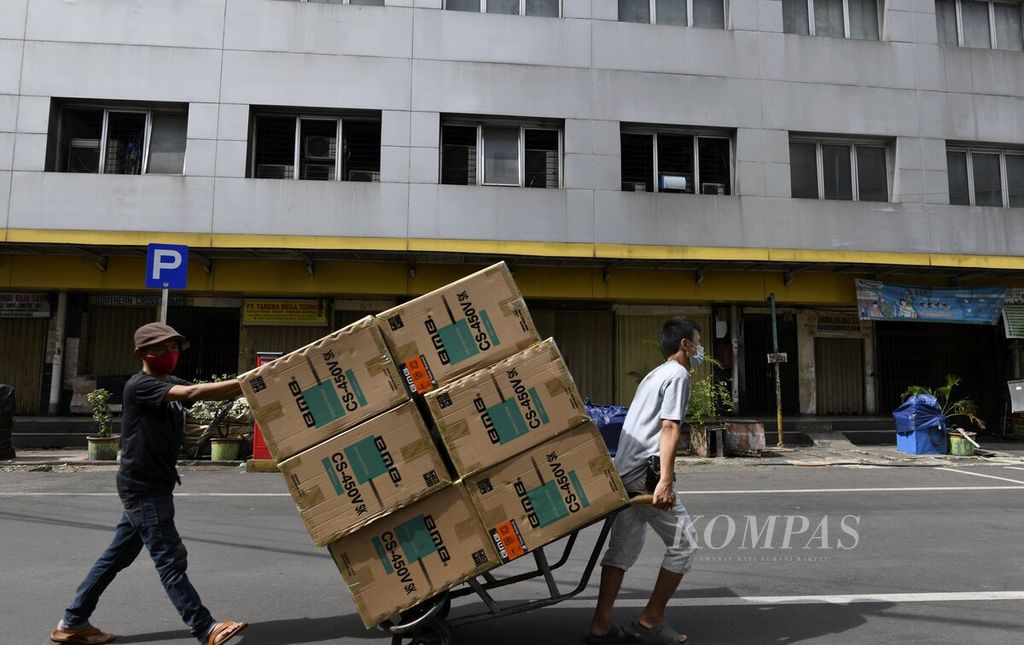 Pekerja membawa sejumlah barang melewati pertokoan HWI-Lindeteves, Glodok, Jakarta Barat, yang tutup saat hari libur nasional pelaksanaan pemilihan kepala daerah (pilkada), Rabu (9/12/2020). 