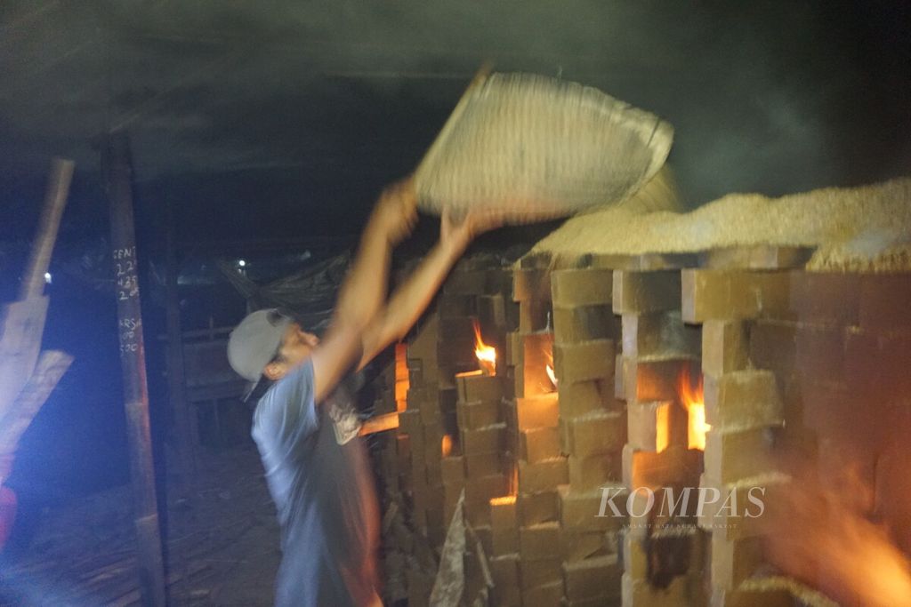 Pekerja menata kayu bakar di tempat pembuatan bata atau tobong di Desa Panggisari, Kecamatan Mandiraja, Kabupaten Banjarnegara, Jawa Tengah, Kamis (6/4/2023) pukul 22.00.