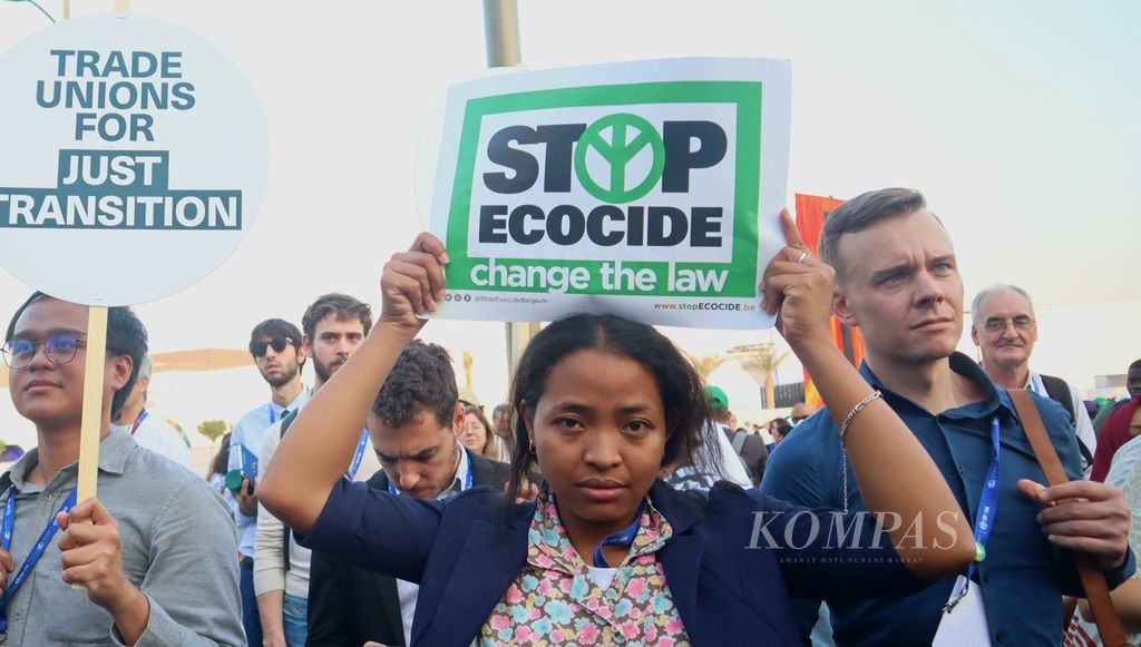 Aktivis gerakan Stop Ecocide International mengangkat poster berisi pesan penghentian pemusnahan lingkungan di lokasi COP28, di Expo Dubai, Dubai, Uni Emirat Arab, Sabtu (9/12/2023).