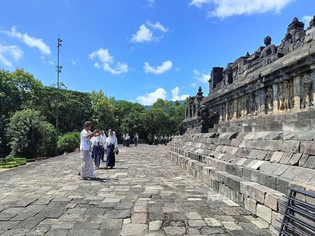 Seorang pemandu wisata, sembari berjalan, memberikan penjelasan perihal sejarah Candi Borobudur kepada rombongan pelajar SMP, Senin (12/2/2024).
