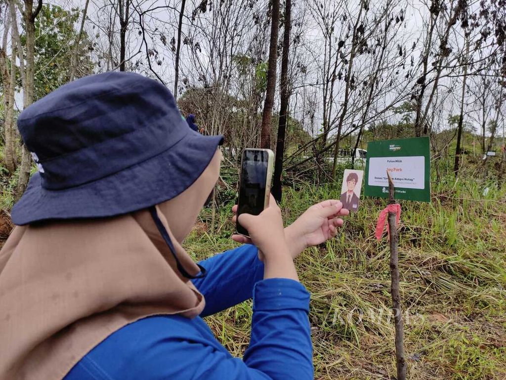 Nadira Hapsari memotret gambar idolanya, Jay Park, seusai menghijaukan Hutan Harapan di Jambi, Jumat (9/2/2024). 