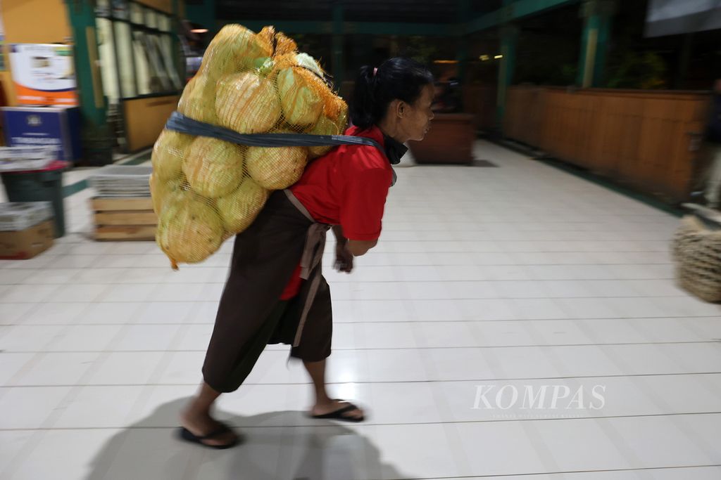 Buruh gendong bernama Kasmi (51) bekerja memindahkan barang milik pedagang di Pasar Beringharjo, Yogyakarta, Selasa (7/3/2023) dini hari. 
