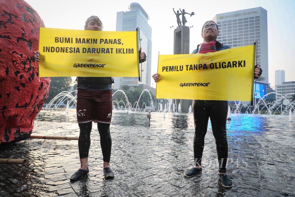 Aktivis Greenpeace membentangkan spanduk protes di sekitar kolam Bundaran HI, Jakarta, Jumat (6/10/2023). Aksi tersebut menyerukan Pemilu 2024 yang bersih dari oligarki.