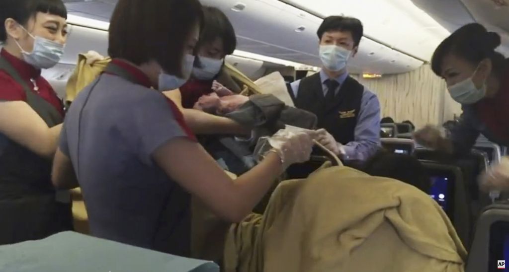 Dalam gambar dari video AP, seorang awak pesawat menggendong bayi yang baru lahir setelah Dr. Angelica Zen, yang tidak terlihat di kanan bawah, melahirkan bayi tersebut dalam penerbangan China Air dari Taiwan pada 7 Oktober 2015. 