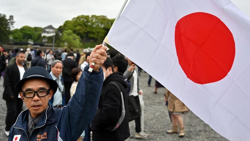 Warga memegang bendera Jepang di luar kompleks Istana Kekaisaran Jepang di Tokyo, Selasa (30/4/2018). Jepang melalui Menteri Keuangan Jepang Shunichi Suzuki menyatakan akan hadir pada pertemuan para menteri keuangan dan gubernur bank sentral G20 di Washington DC, AS, pekan depan. 