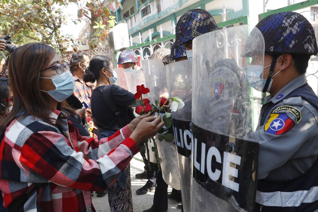 Pengunjuk rasa memberikan mawar kepada polisi saat empat aktivis yang ditahan hadir di pengadilan di Mandalay, Myanmar, 5 Februari 2021. 