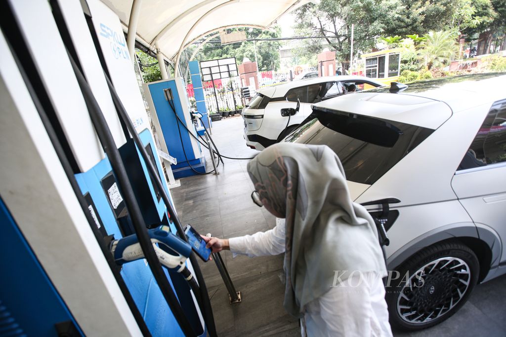 Pengguna mobil listrik mengisi daya listrik pada mobilnya di stasiun pengisian kendaraan listrik umum (SPKLU) di kantor PLN di kawasan Gambir, Jakarta Pusat, Senin (18/12/2023). PT PLN (Persero) membuka diri untuk bekerja sama dengan semua pihak untuk menambah ketersediaan <i>charging station</i> seperti SPKLU, stasiun penukaran baterai kendaraan listrik umum (SPBKLU), dan stasiun pengisian listrik umum (SPLU) guna mempercepat ekosistem kendaraan listrik di Indonesia. 