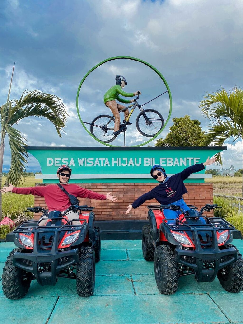 Wisatawan yang mengendarai motor ATV berfoto dengan latar belakang tugu sepeda di Desa Wisata Hijau Bilebante. Berkeliling desa wisata itu menjadi salah satu kegiatan yang dipadukan dengan buka puasa bersama.