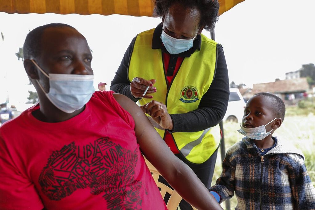 Seorang anak memperhatikan petugas medis yang sedang menyuntikkan vaksin Covid-19 menggunakan vaksin AstraZeneca kepada ayahnya di Nairobi, Kenya, 14 Agustus 2021. 
