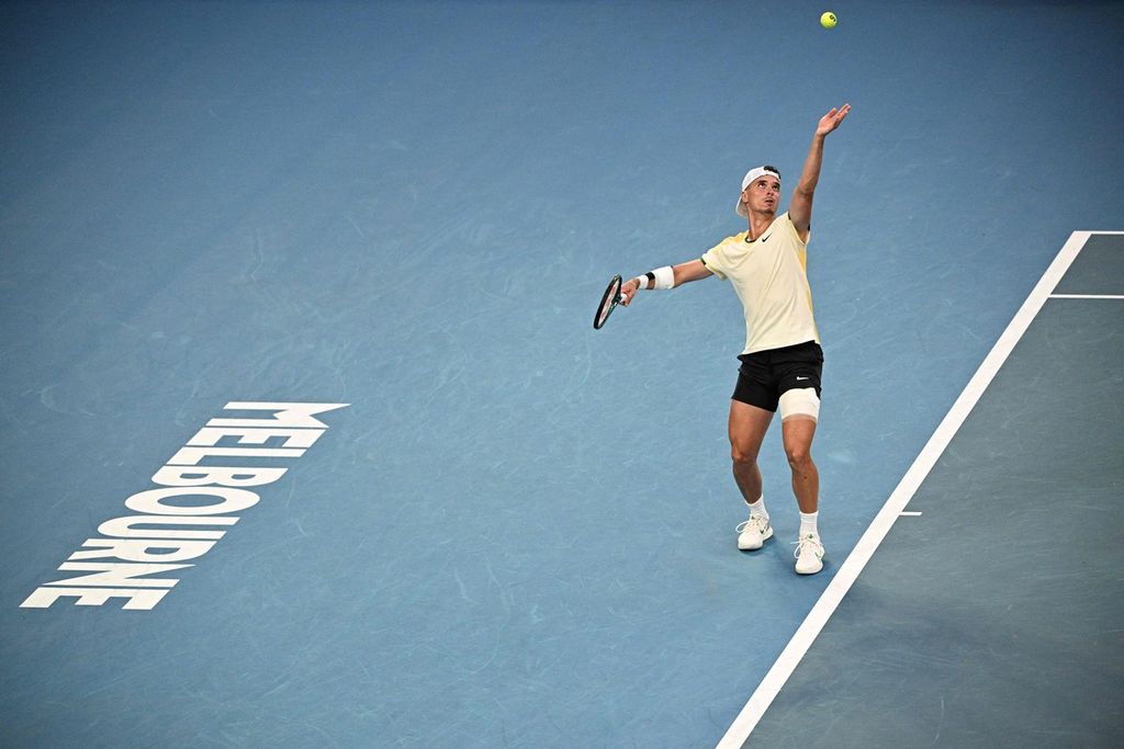Petenis Kroasia, Dino Prizmic, melakukan servis saat melawan petenis Serbia, Novak Djokovic, pada babak pertama Australia Terbuka, Minggu (14/1/2024).