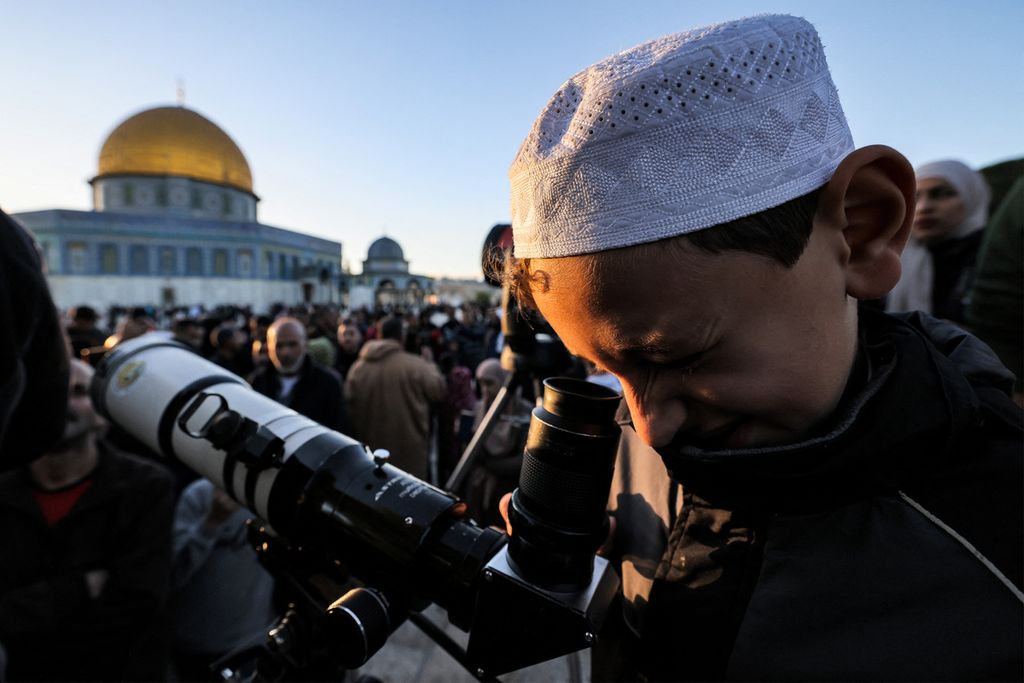 Warga memeriksa teleskop untuk mencari bulan sabit baru yang menandai dimulainya Idul Fitri, di akhir bulan suci Ramadhan, dekat Dome of the Rock di kompleks Masjidil Aqsa di Kota Tua Jerusalem pada 20 April 2023. 