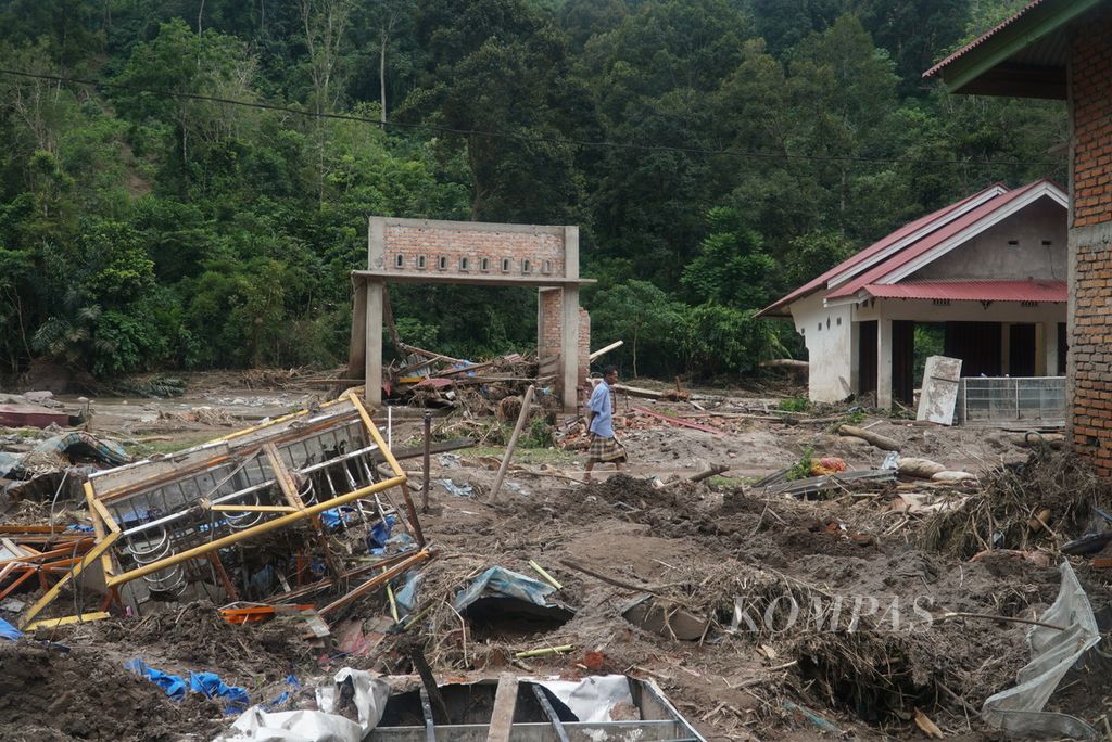 Warga melintas di sekitar rumah yang hancur diterjang banjir bandang di Kampung Batu Bala, Nagari Ganting Mudiak Utara Surantih, Kecamatan Sutera, Kabupaten Pesisir Selatan, Sumatera Barat, Selasa (12/3/2024). 