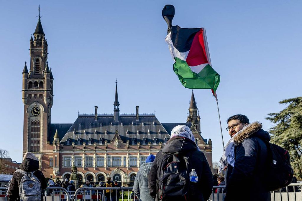 Seorang pengunjuk rasa mengibarkan bendera Palestina di depan Istana Perdamaian (Peace Palace), markas Mahkamah Internasional (ICJ), menjelang persidangan kasus dakwaan genosida israel yang diajukan Israel di Den Haag, Belanda, Jumat (26/1/2024). 
