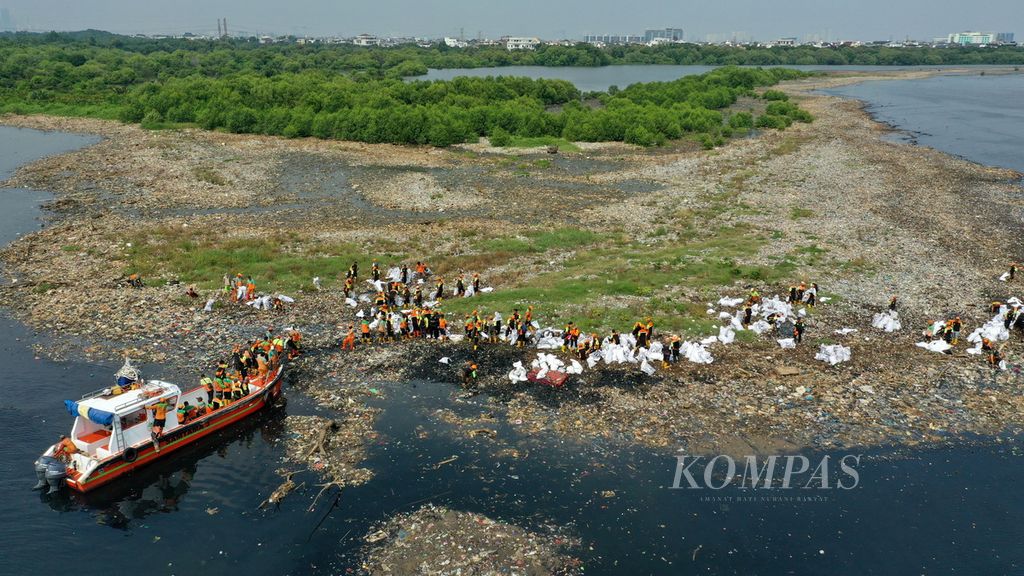 Foto udara petugas gabungan Dinas Lingkungan Hidup DKI Jakarta membersihkan sampah yang menumpuk di hutan mangrove Muara Angke, Penjaringan, Jakarta Utara, Kamis (13/7/2023). Pembersihan sampah sepanjang dua kilometer di pesisir hutan mangrove tersebut sudah berlangsung sejak Rabu (12/7/2023). 