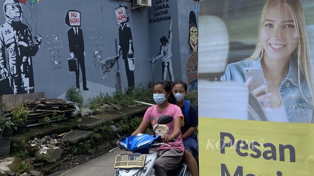 Warga melintasi mural yang dibuat untuk melawan penyebaran informasi palsu di masyarakat di Jalan KH Hasyim Ashari, Tangerang, Banten, Senin (22/2/2021). 