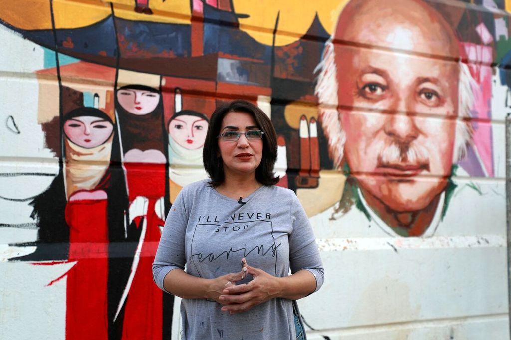 Foto pertama memperihatkan saat Seniman Irak  Wijdan al-Majed tengah melukis wajah penyair Irak Muzzafar al-Nawab di sebuah dinding beton di Baghdad pada Selasa (26/4/2022). Foto kedua  saat Wijdan al-Majed berbicara dalam sesi wawancara.