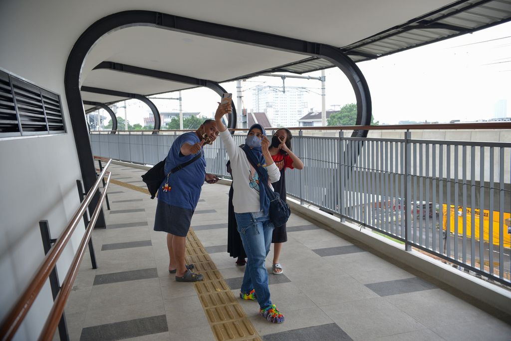 Sejumlah warga berfoto di jembatan layang penyeberangan orang simpang temu di Stasiun MRT Lebak Bulus, Lebak Bulus, Jakarta Selatan, Jumat (30/12/2022).