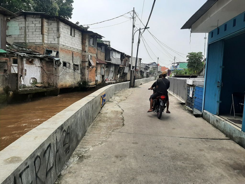 Warga melintasi jalan dengan perbatasan tanggul yang dibangun di kawasan Kampung Tengah, Kramat Jati, Jakarta Timur, Kamis (20/10/2022). Tanggul tersebut untuk mengantisipasi terjadinya banjir.