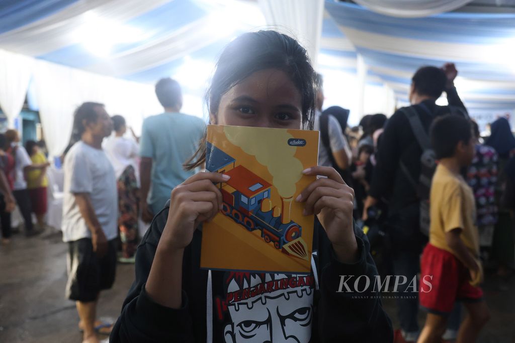 Seorang anak memperlihatkan buku yang didapatkan dari calon wakil presiden nomor urut 2, Gibran Rakabuming Raka, di Jalan Rawa Bebek 1, Penjaringan, Jakarta Utara, Jumat (1/12/2023).