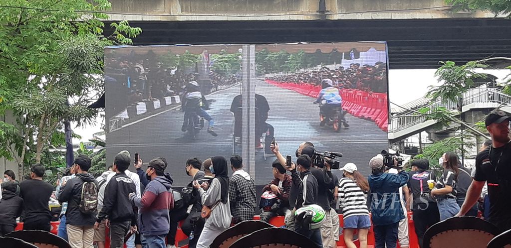 Layar besar menampilkan gambar dua sepeda motor balap yang akan melaju di Jalan Inspeksi Kali Ancol, Pademangan, Jakarta Utara, Minggu (16/1/2022). Polda Metro Jaya mengadakan <i>street race </i>untuk latihan pembalap motor jalanan.