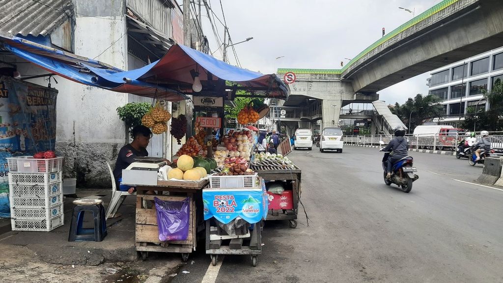 Pedagang buah, Johan Laksamana S (30), berdagang di dekat jalan layang, Pasar Kebayoran Lama, Jakarta, Selasa (14/3/2023). 