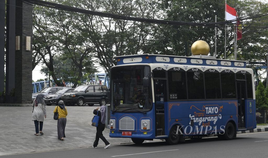 Penumpang berjalan setelah turun dari bus Trans Tayo di Jalan Daan Mogot, Kota Tangerang, Banten, Minggu (31/5/2020).