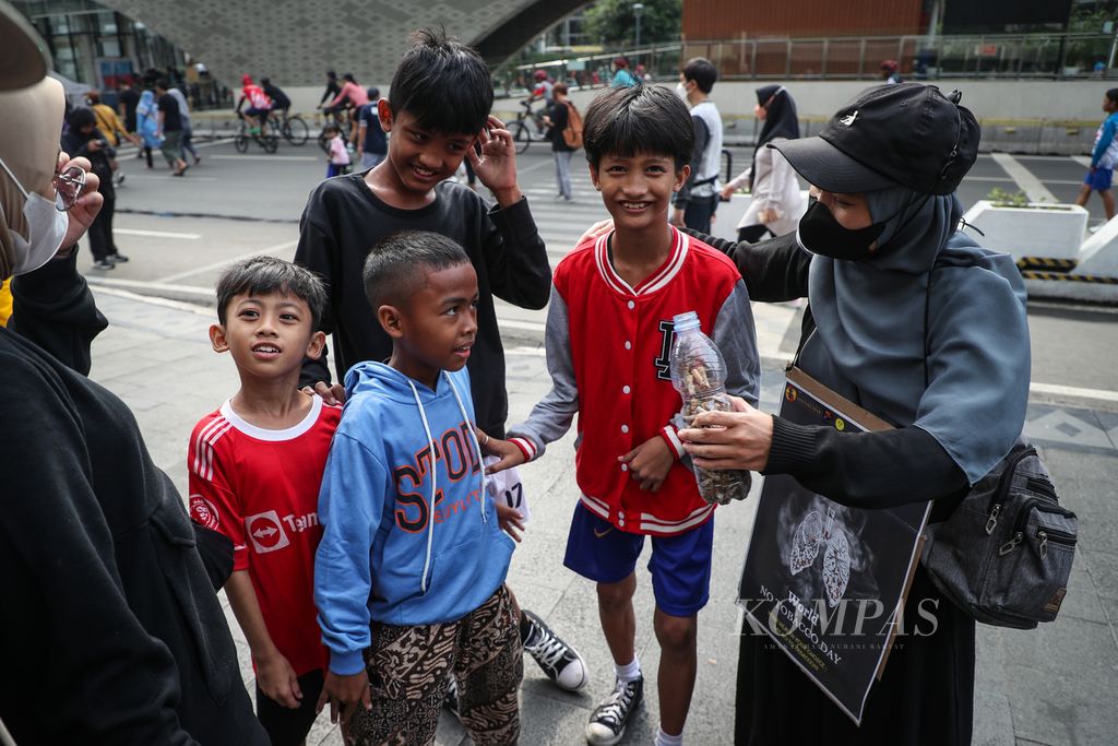 Sukarelawan menyosialisasikan bahaya rokok kepada anak-anak dalam kegiatan Plogging Cigarette Butt di kawasan Bundaran HI, Jakarta, Minggu (28/5/2023). 