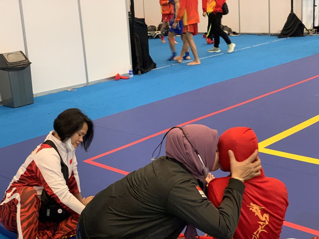Endang Tri Murni (hitam) memeluk sembari memberikan semangat buat anaknya, Nasya Aulia Zahra (merah), sesaat setelah kalah pada Kejuaraan Dunia Wushu Yunior 2022 di Tangerang, Banten, Kamis (8/12/2022).