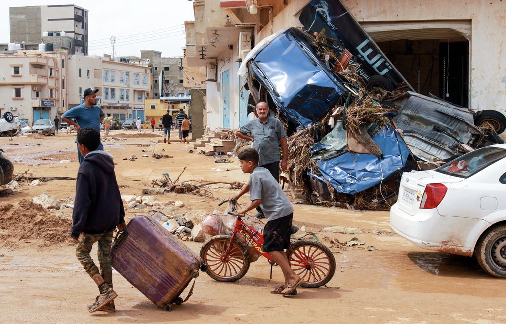 Seorang anak laki-laki menarik koper melewati puing-puing di daerah yang rusak akibat banjir bandang di Derna, Libya timur, pada 11 September 2023. Banjir bandang di Libya timur menewaskan lebih dari 2.300 orang di kota pesisir Derna saja.