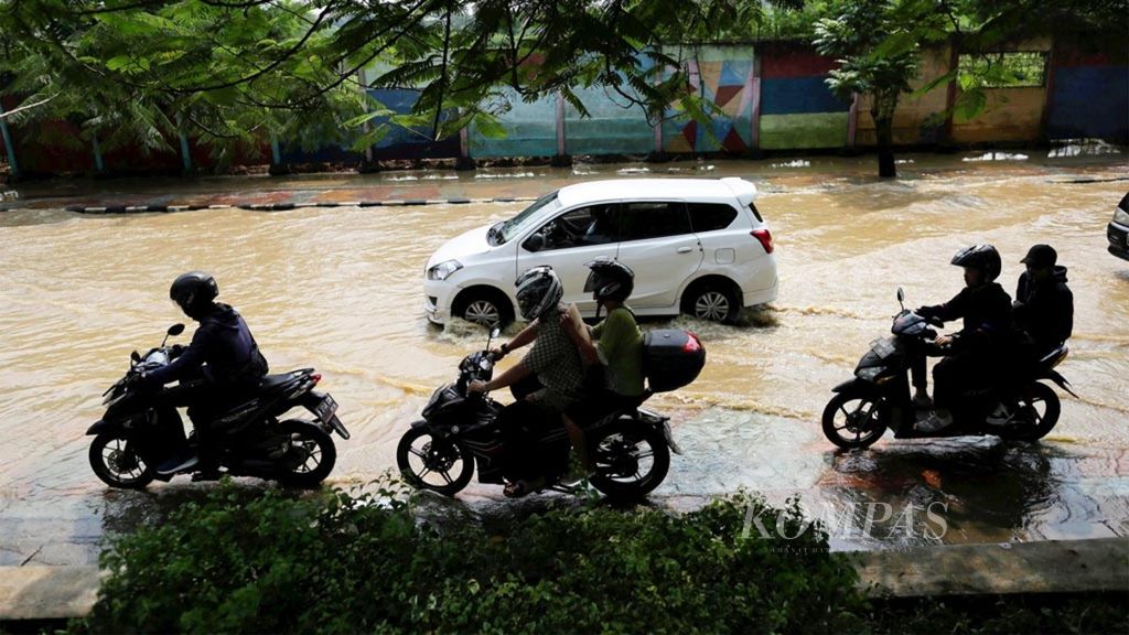 Pengendara melalui Jalan Imam Bonjol, Kota Tangerang, Banten, yang kebanjiran akibat meluapnya Kali Cisadane, Jumat (26/4/2019). Meluapnya Kali Cisadane menyebabkan sebagian Kota Tangerang, terutama daerah-daerah yang dilalui kali tersebut, lumpuh.