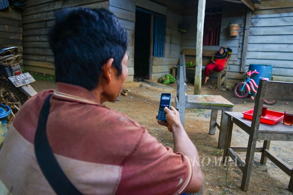 Atumi (52), dan istrinya Musriah (43), warga Lalomerui, Routa, Konawe, Sulawesi Tenggara, mengecek telepon sehabis berkebun pada Rabu (20/7/2022). Akses jaringan telepon dan internet telah masuk di pelosok Sultra ini sejak setahun terakhir. Warga memanfaatkan jaringan meski hanya ada satu provider, yaitu jaringan XL.
