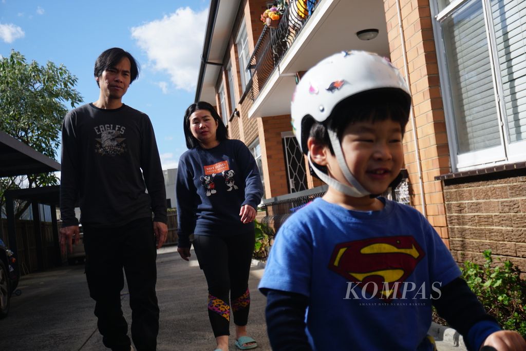 Martin Cahyo (45, kiri) dan Lily Lumintang (43) menemani anak bungsu mereka, Raphael (3), bermain ketika ditemui di rumah mereka di Kew, di timur Melbourne, Australia, pada Sabtu (24/8/2024). 