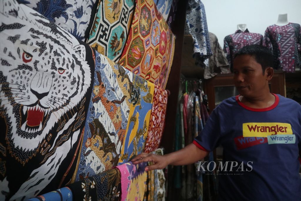 Gunisa (51) menata dagangannya di Pasar Batik Trusmi di Kabupaten Cirebon, Jawa Barat, Selasa (26/4/2022). Pedagang di pasar tersebut menanti berkah dari arus mudik Lebaran. Pemilik Batik Nefa ini menyiapkan aneka motif batik tulis seharga Rp 250.000 hingga Rp 1 juta lebih.