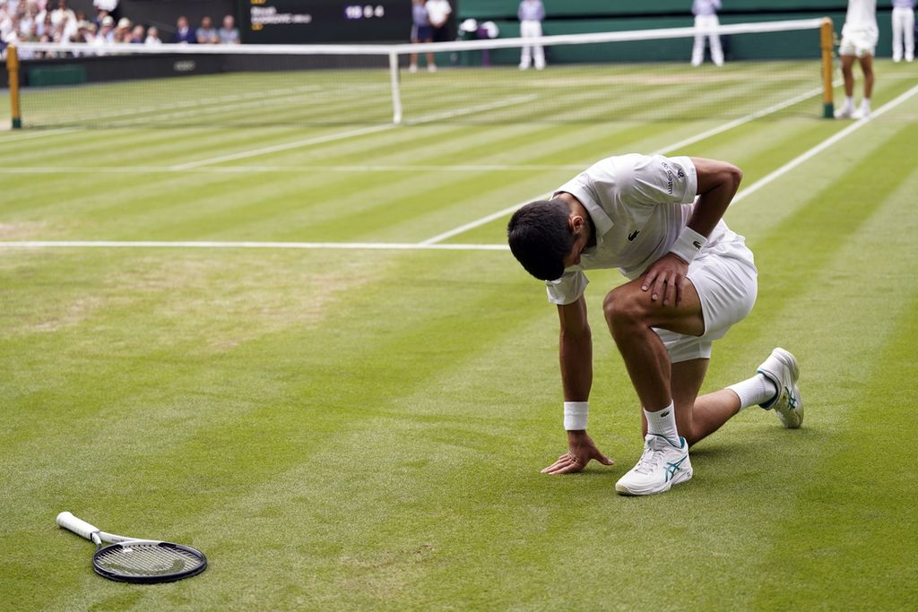 Novak Djokovic juga terjatuh karena lapangan licin saat melawan Carlos Alcaraz pada laga final Grand Slam Wimbledon di The All England Tennis Club, Wimbledon, Inggris, Minggu (16/7/2023). 