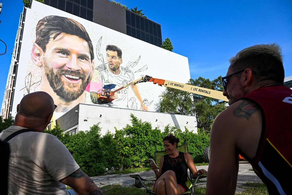 Warga Miami, Florida, Amerika Serikat, menyaksikan pelukis Argentina, Maximiliano Bagnasco (atas), membuat mural Lionel Messi. 10 Juli 2023. Messi telah menandatangani kontrak di Inter Miami, klub Liga AS, hingga 2025.