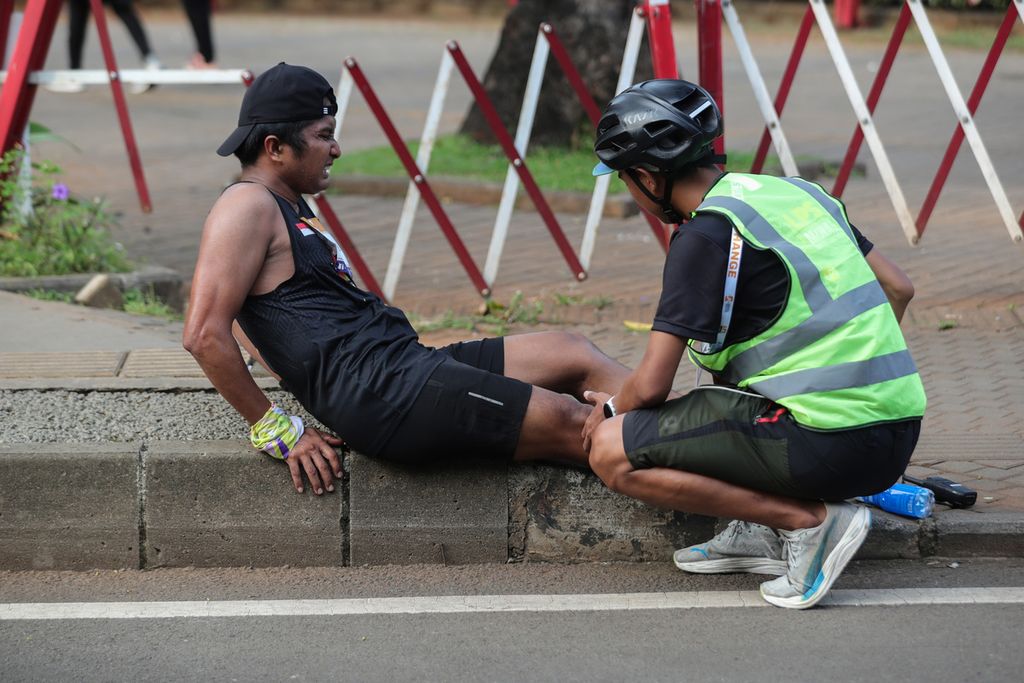 Petugas kesehatan menangani pelari yang cedera di kawasan Gelora Bung Karno, Jakarta, Minggu (2/7/2023). Harian <i>Kompas</i> bersama Lembaga Penjamin Simpanan (LPS) yang didukung oleh Pemerintah Provinsi DKI Jakarta menyelenggarakan LPS Monas Half Marathon. 