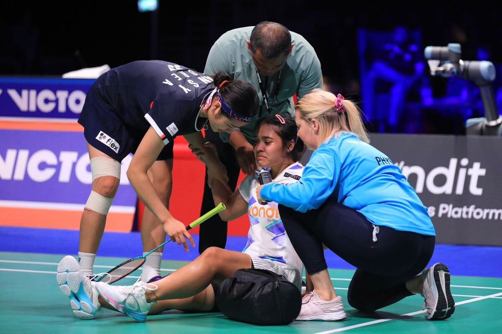 Gregoria Mariska Tunjung dihampiri lawannya pada semifinal Denmark Terbuka, An Se-young (kiri), saat duduk di lapangan karena sakit pada paha dan pinggang. Gregoria mundur saat skor 20-22, 12-12 dalam pertandingan yang berlangsung di Jyske Arena, Odense, Sabtu (19/10/2024).