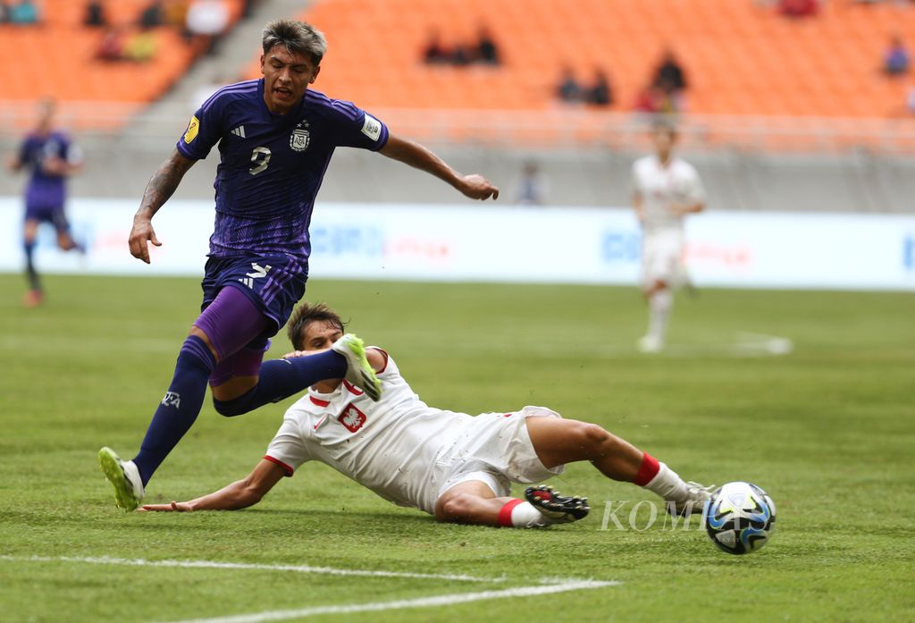 Polish player, Maksymilian Sznaucher (bottom), fell while pursuing the ball against Argentine player, Agustin Ruberto, during the Group D preliminary match of the 2023 U-17 World Cup at Jakarta International Stadium (JIS), Jakarta on Friday (17/11/2023). Argentina advanced to the round of 16 after defeating Poland 4-0.